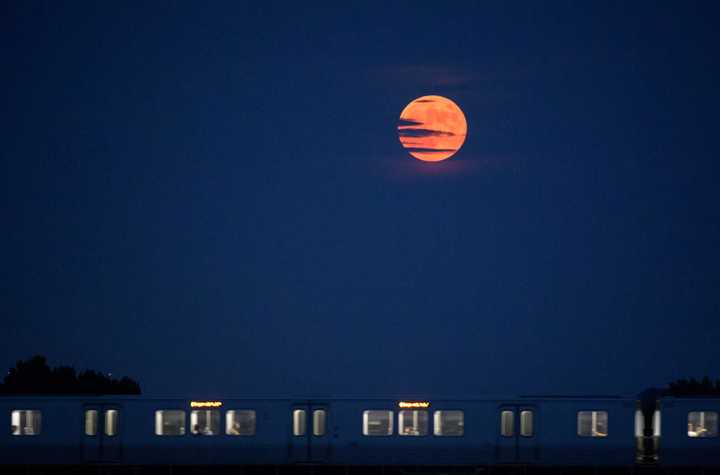 The Strawberry Moon rises as a Metrorail car crosses the Potomac River in 2019.&nbsp; &nbsp; &nbsp;
