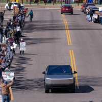 <p>A Tesla Cybertruck drives past "Tesla Takedown" protesters in Minneapolis on March 22, 2025.</p>
