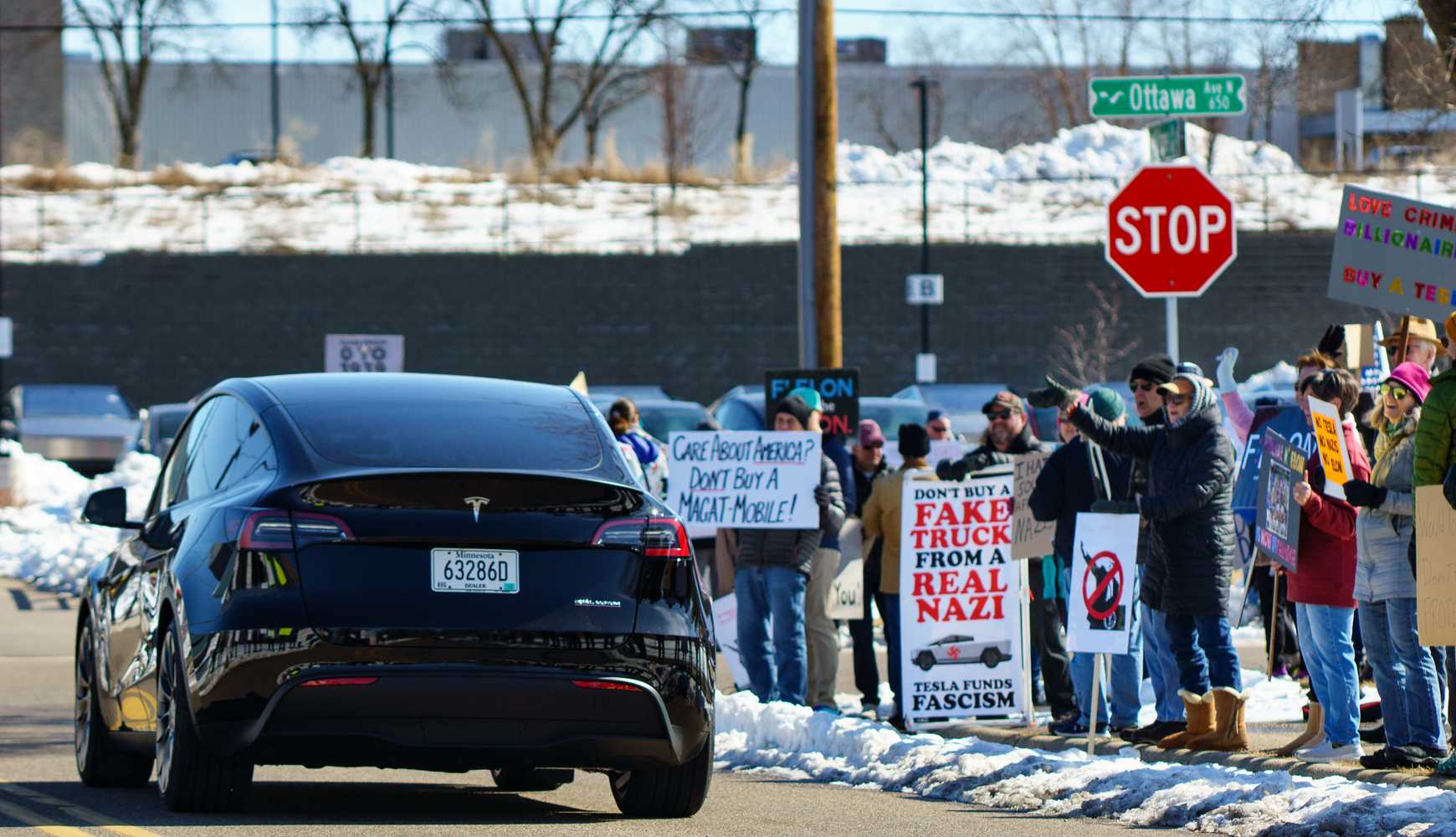 
"Tesla Takedown" protesters demonstrate in Minneapolis as a Tesla car passes by them.
