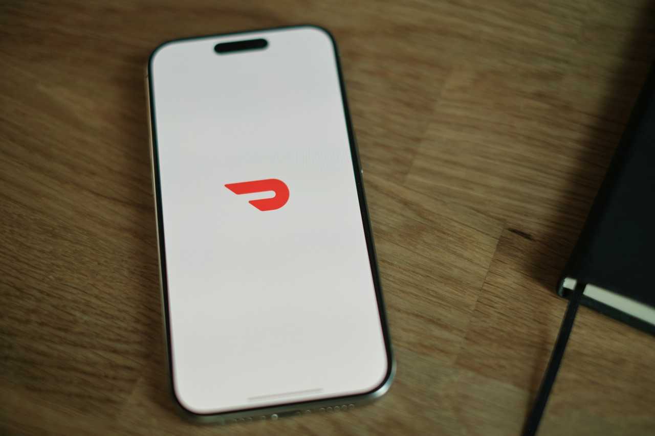 A smartphone displaying the DoorDash logo. A smartphone displaying the DoorDash logo.