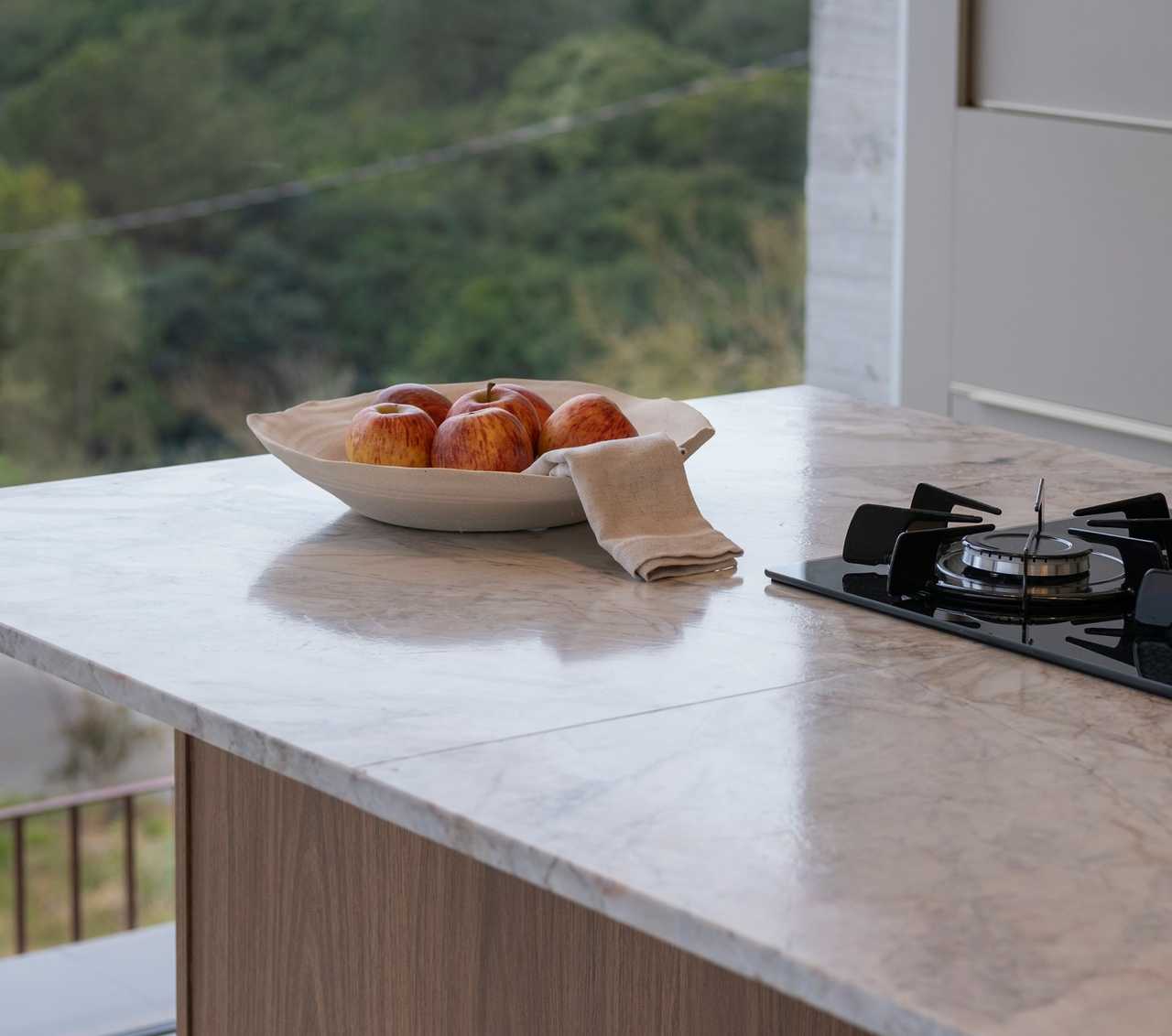 A kitchen countertop with a bowl of apples and a stove. A kitchen countertop with a bowl of apples and a stove.