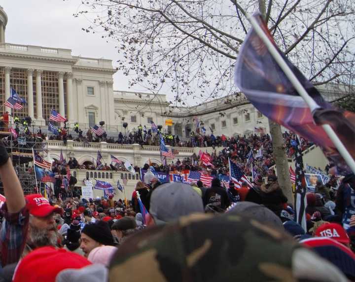 The outside of the U.S. Capitol during the Jan. 6 insurrection. An "Appeal to Heaven" flag is seen carried by a rioter.