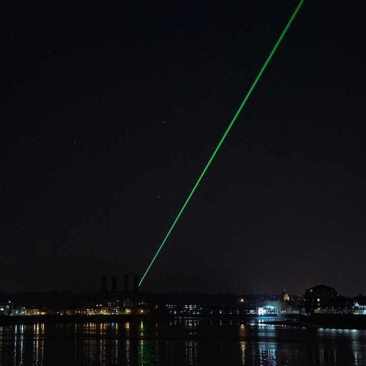 A green laser fires across the night sky. 