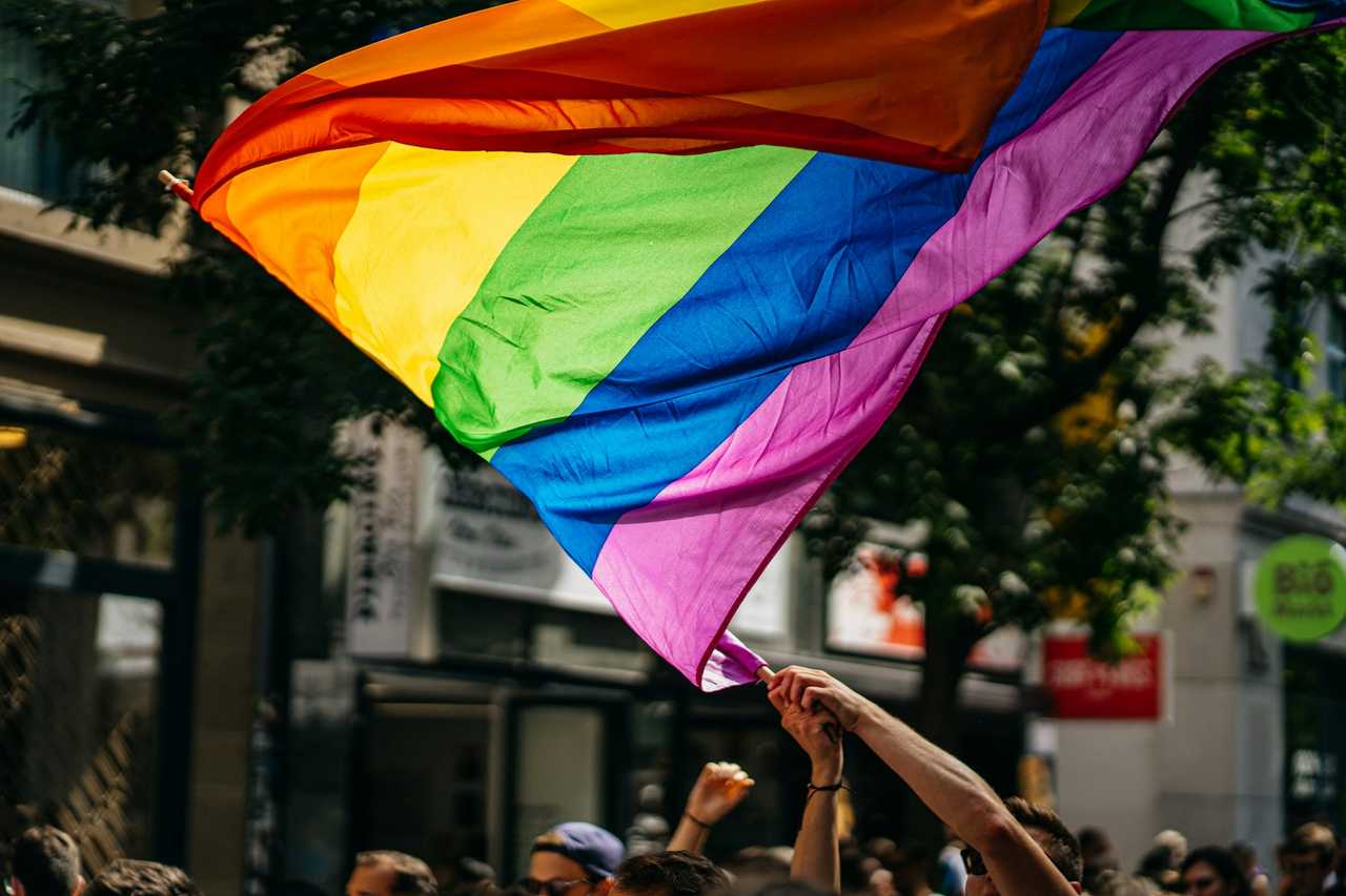 A person waving an LGBTQ+ pride flag.