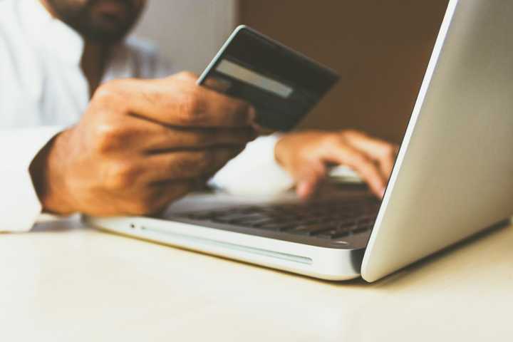 A man holding a credit card and typing on a laptop.