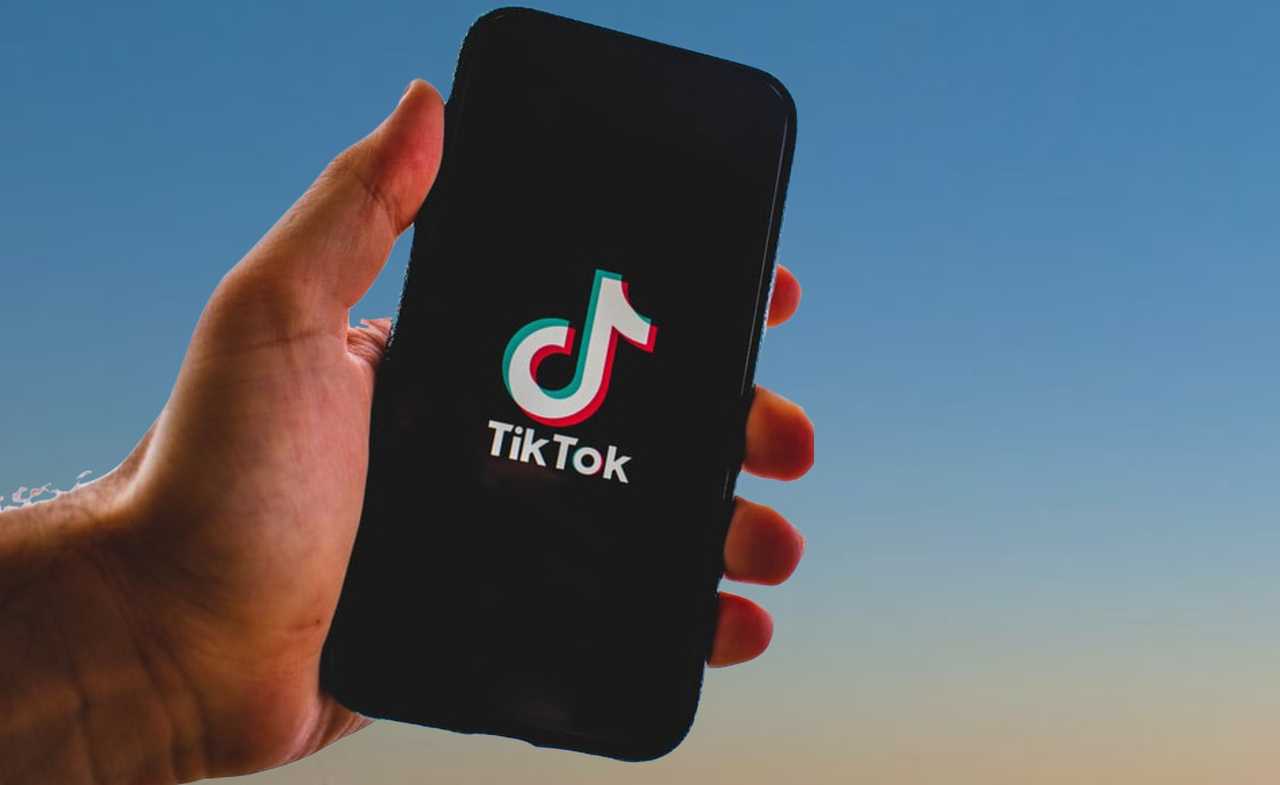 A hand holding a smartphone displaying the TikTok logo.