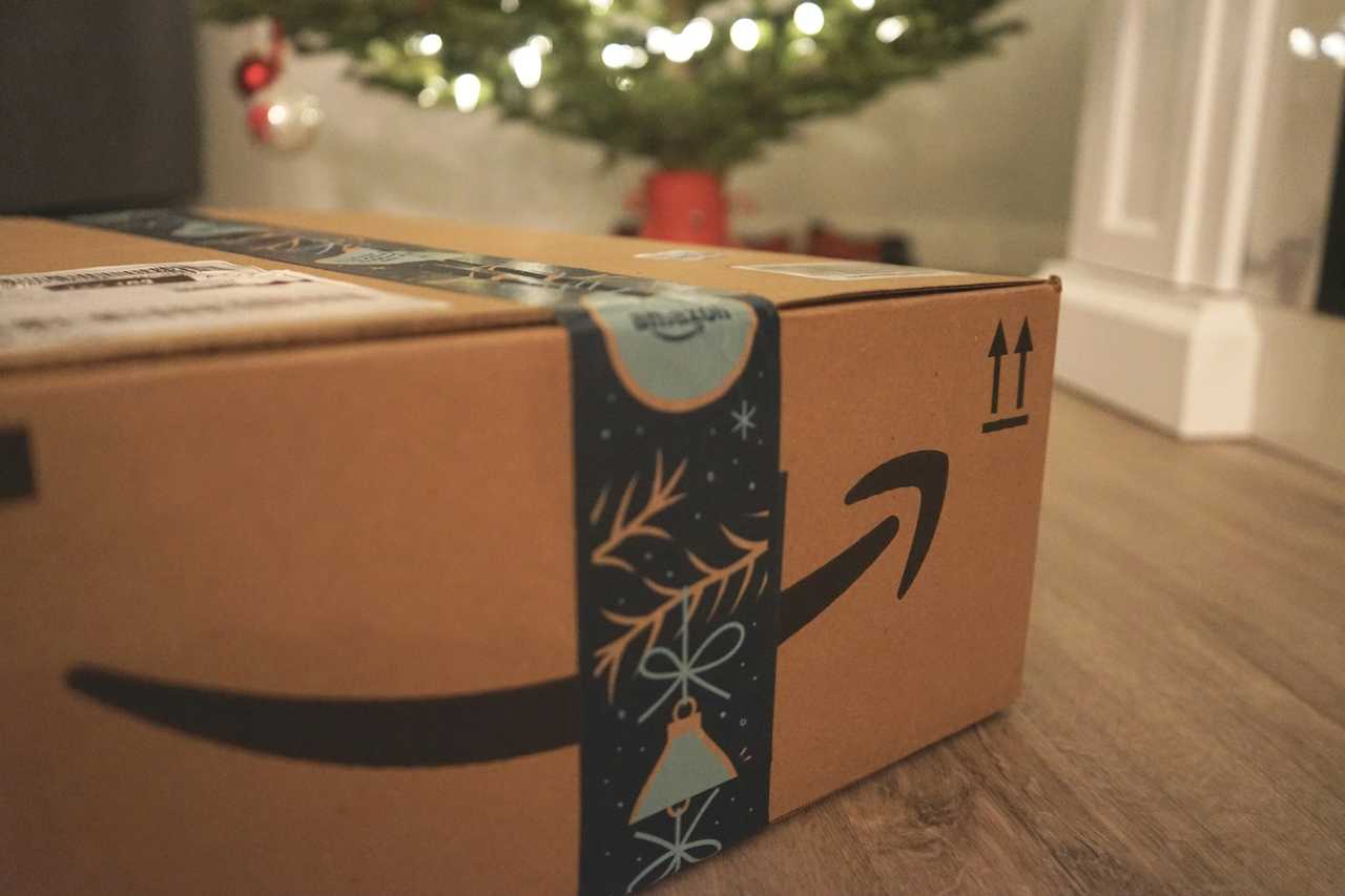 An Amazon package with a Christmas tree in the background. An Amazon package with a Christmas tree in the background.